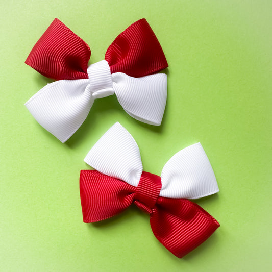 Two red and white hair bows on a green background