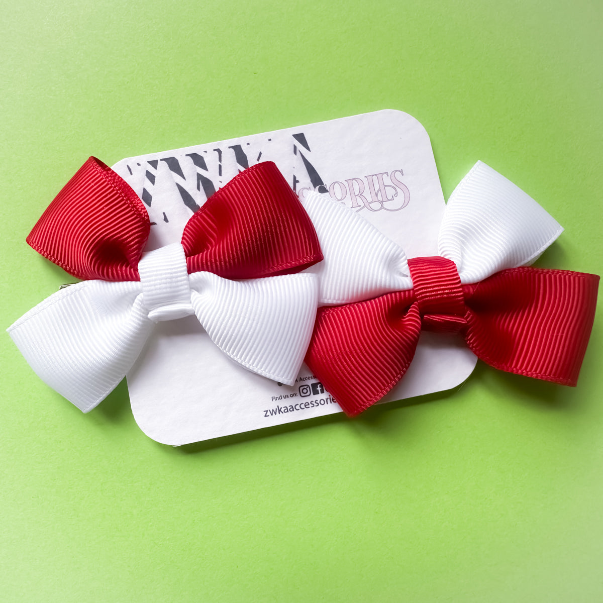 Pair of England Red and white hair bows on a backing card with a green background. Perfect for football match days and World Cup celebrations.