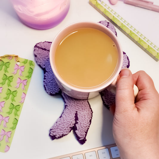 Handmade lilac bow mug rug on desk with tea mug