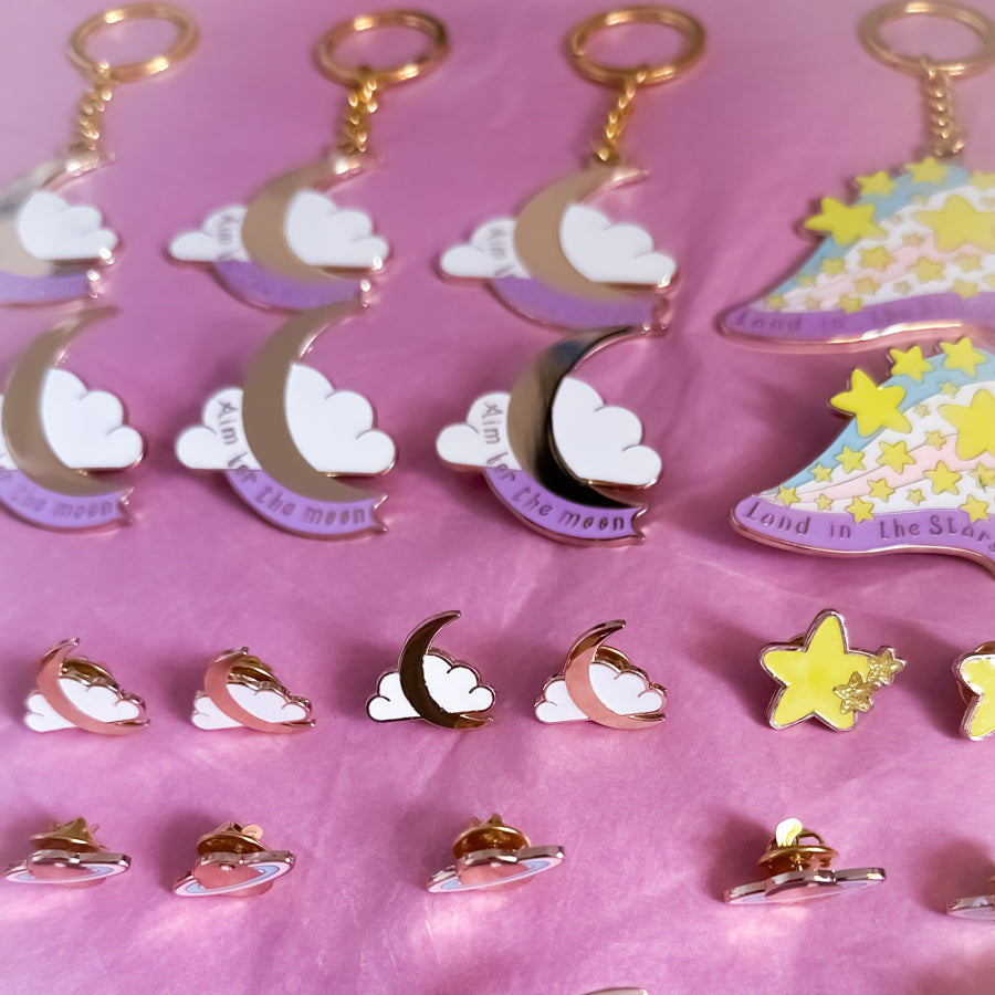 Collection of moon and cloud-themed keychains on a pink background