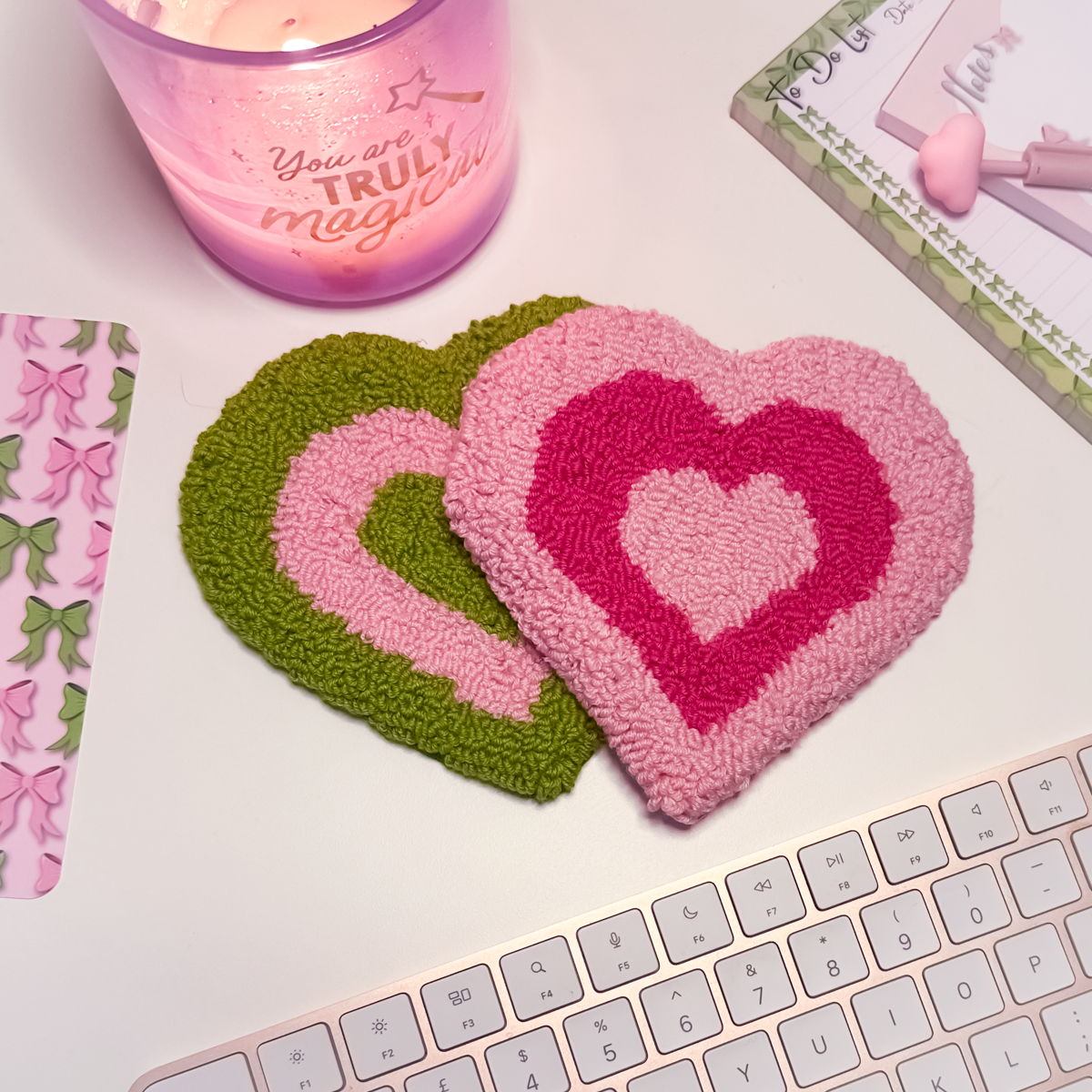 Heart-shaped mug rug coasters on a desk with a candle and stationery items.