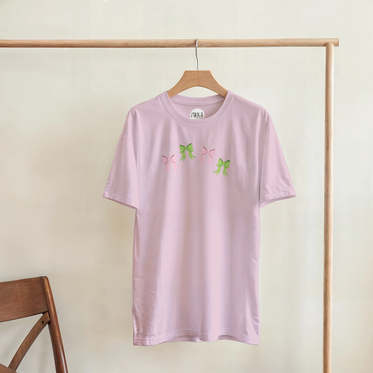 Pink t-shirt with pink and green bow hanging on a coat hanger