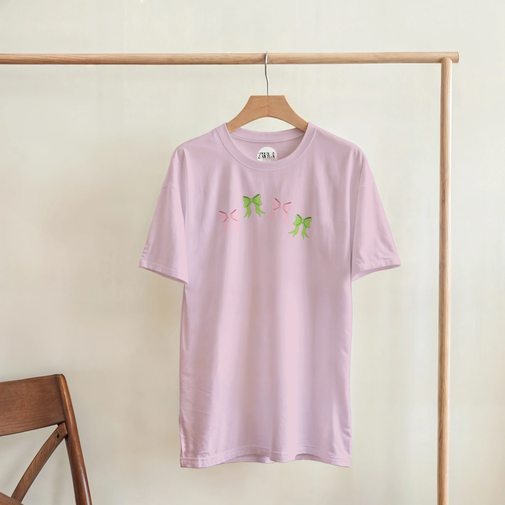 Pink t-shirt with pink and green bow hanging on a coat hanger