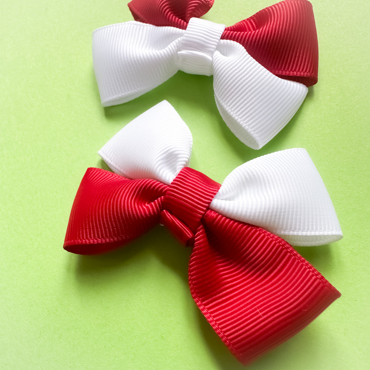 Close up of red and white hair bows on a green background