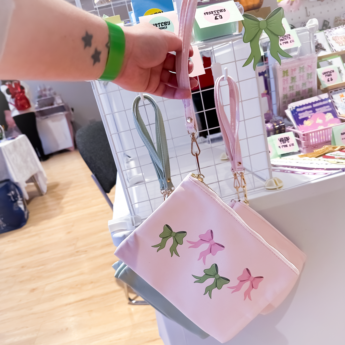 Pink accessory bag with green bow pattern, clutch-style zipper pouch