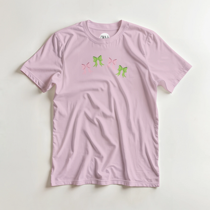 Pink t-shirt with pink and green bow design flat lay
