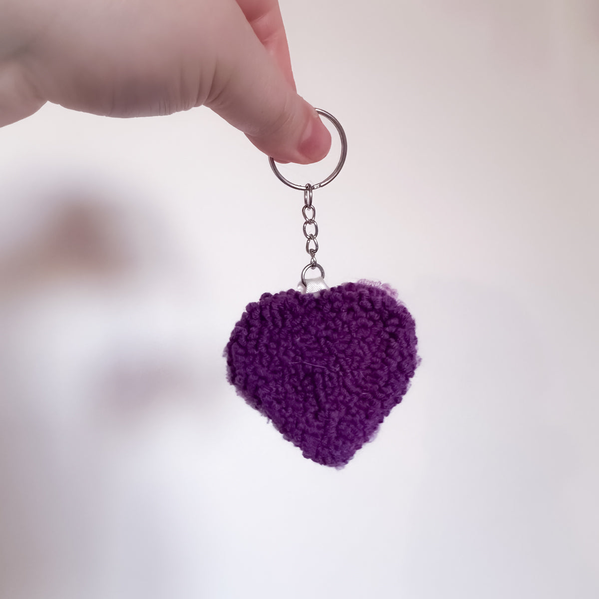 Purple heart-shaped keychain held by a hand
