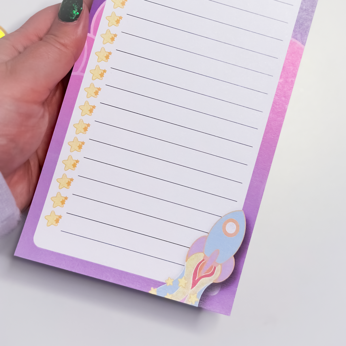 Close-up of Land in the Stars to-do list pad showing lined paper and whimsical rocket illustration at the bottom of the page