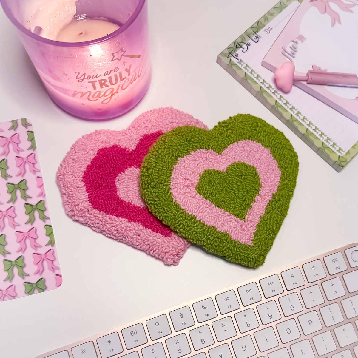 Heart-shaped coasters on a desk with a candle and stationery items.
