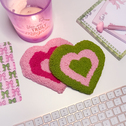 Heart-shaped coasters on a desk with a candle and stationery items.