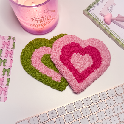 Heart-shaped mug rug coasters on a desk with a candle and stationery items.