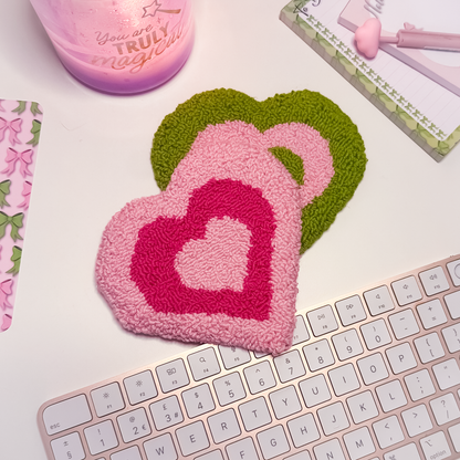 Heart-shaped pink and green coasters on a keyboard with a lilac candle in the background.