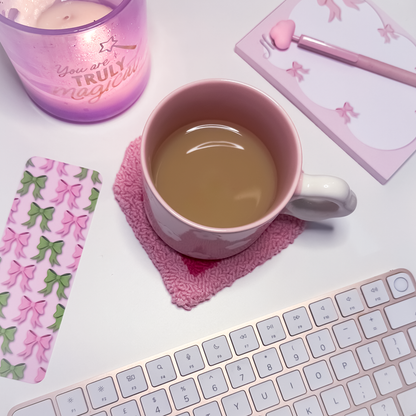 Pink mug with tea on a pink heart shaped mug rug with a keyboard and decorative items.