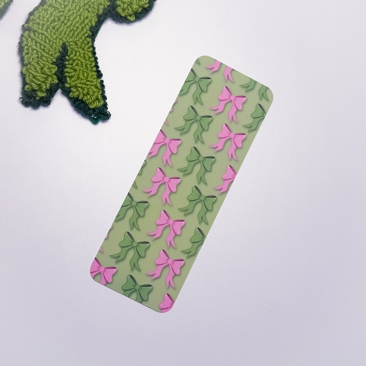 Rectangular green bookmark with pink and green bow pattern