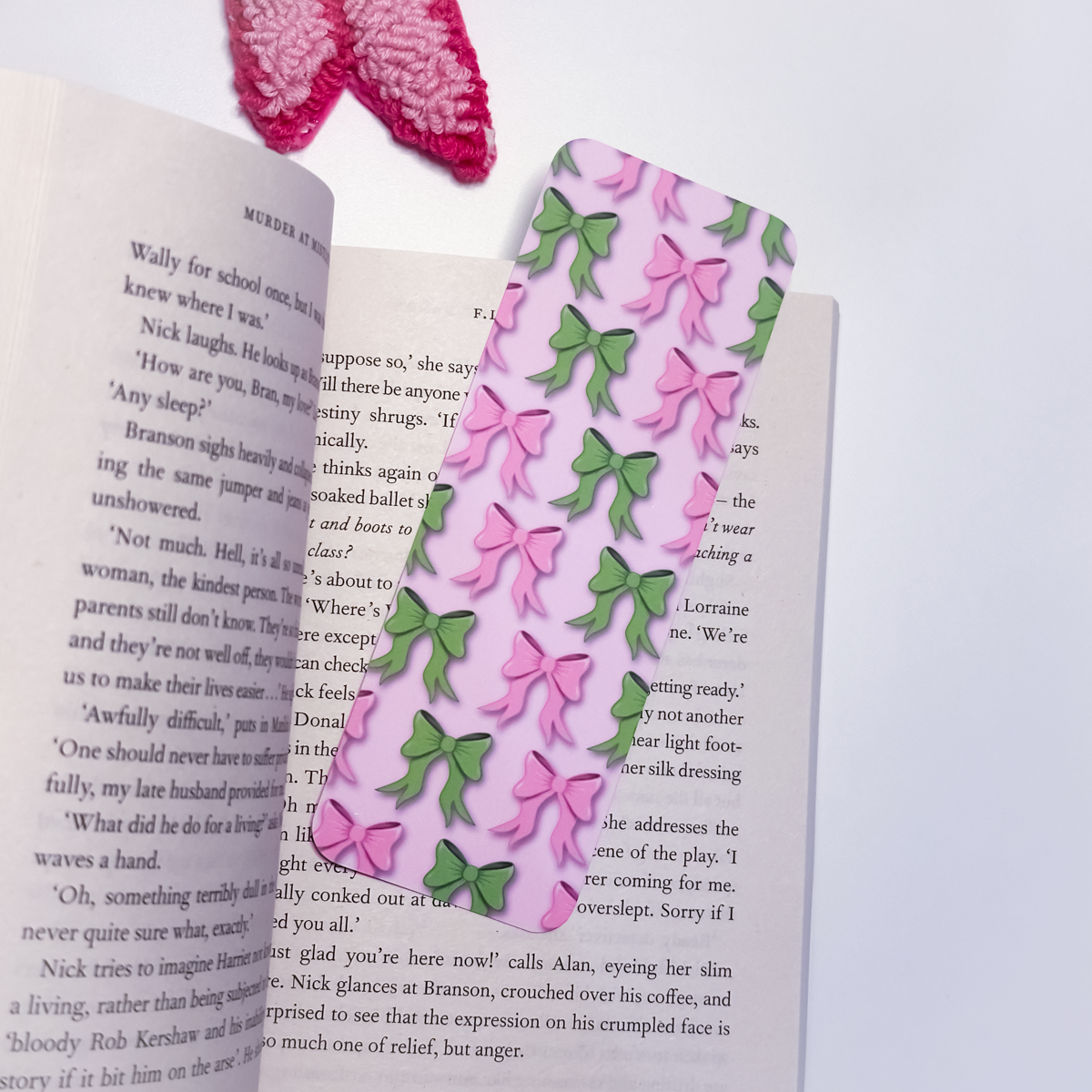 Open book with a pink bookmark with pink and green bows on a white background