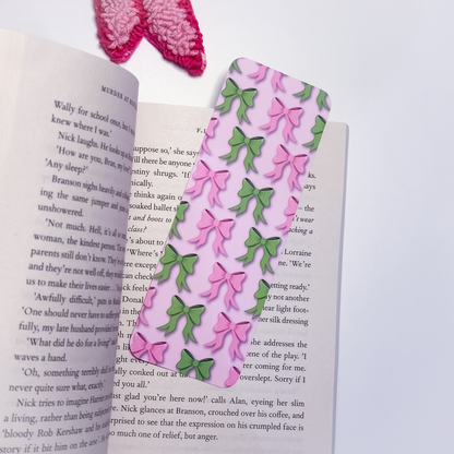 Open book with a pink bookmark with pink and green bows on a white background