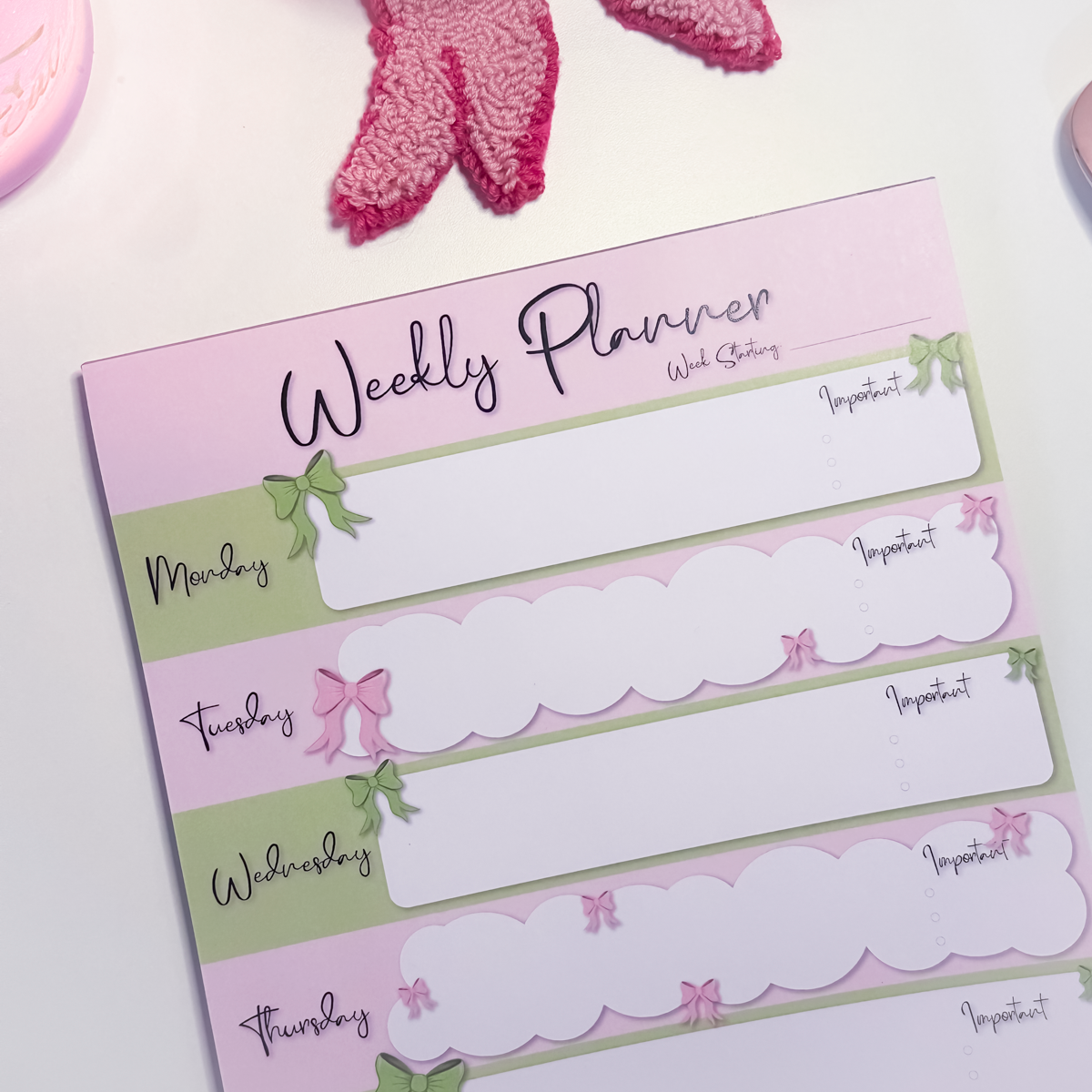 Close up of A4 weekly planner notepad with pink and green bow design, Monday to Sunday layout and tick circles for tasks
