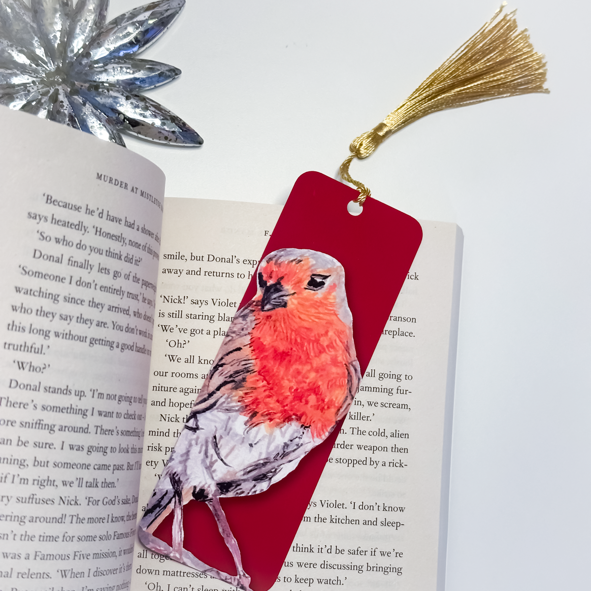 Bird-themed bookmark with gold tassel on an open book